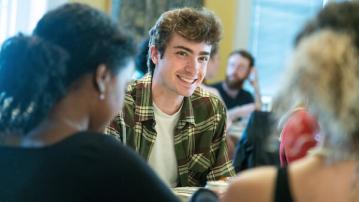 A student smiles at the camera in a busy classroom