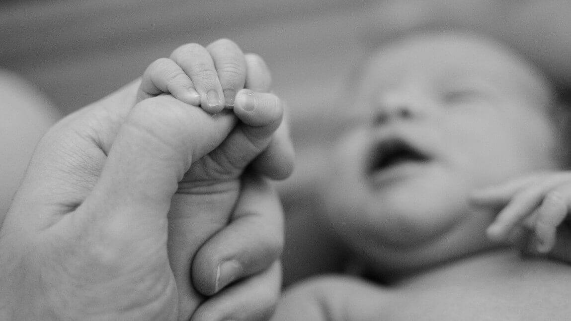 newborn holding mother's finger