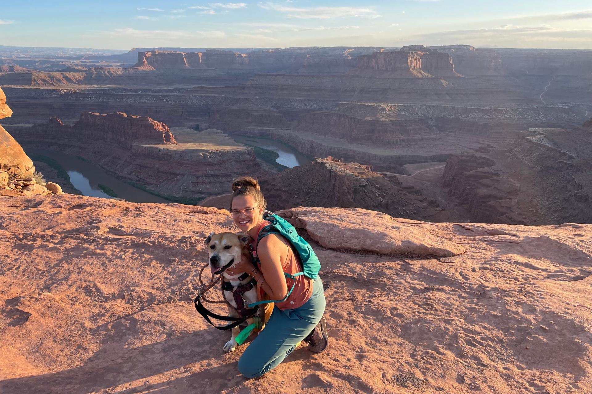young woman kneeling next to dog in front of Grand Canyon