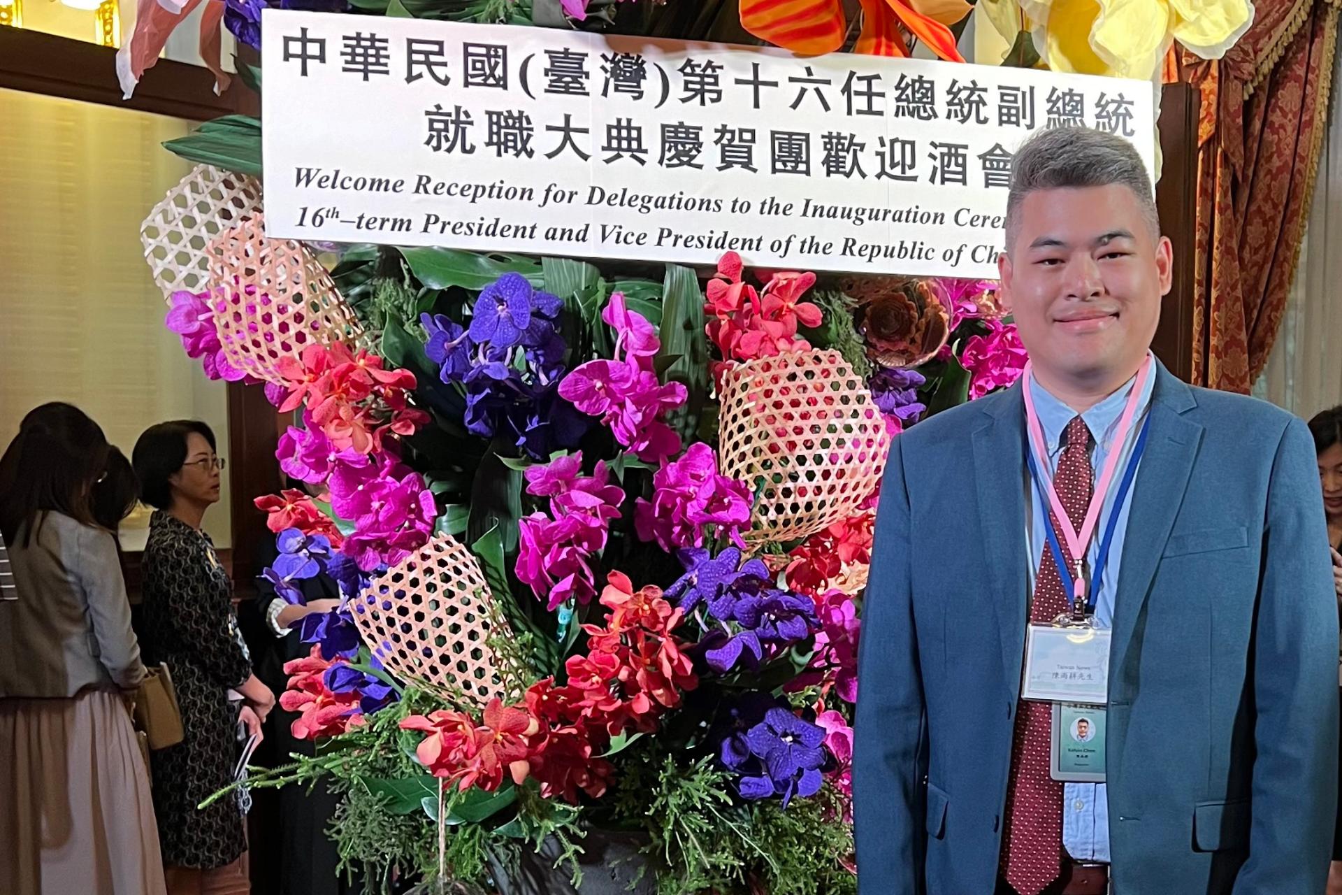 man in blue suit standing in front of flowers and sign at Chinese convention