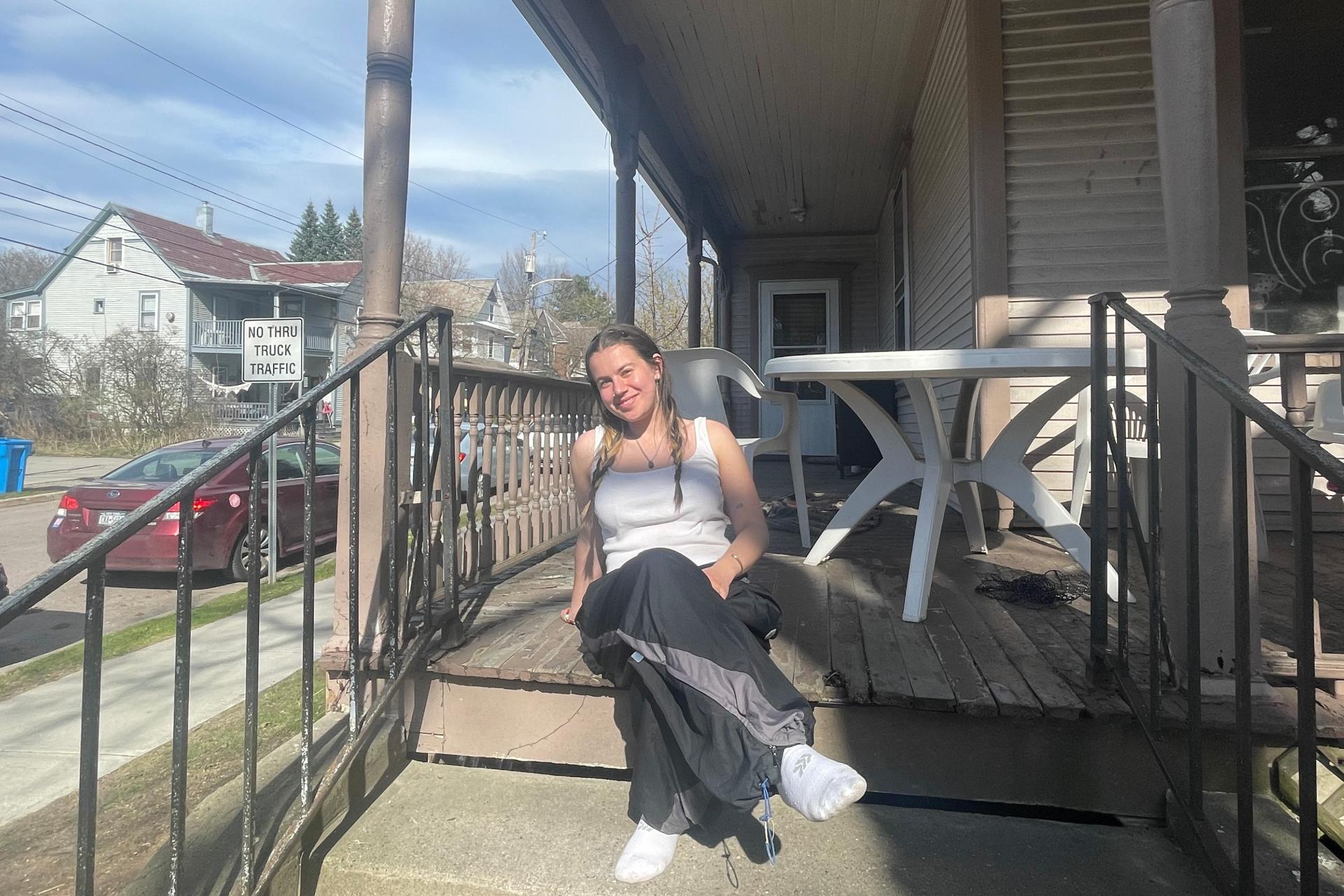 young woman with legs crossed sitting on porch steps