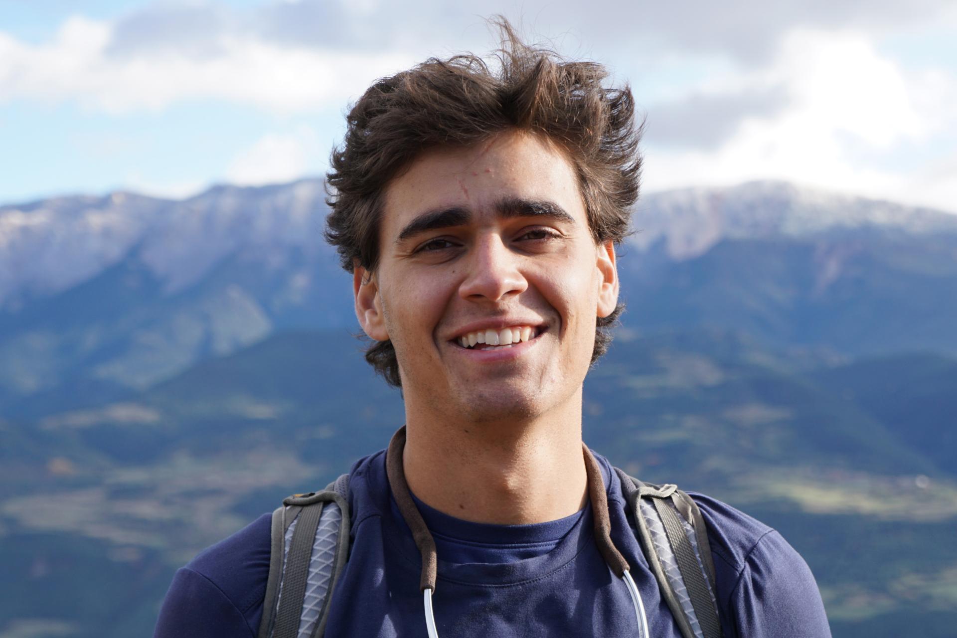 Student Logan Sands standing on mountain ridge smiling