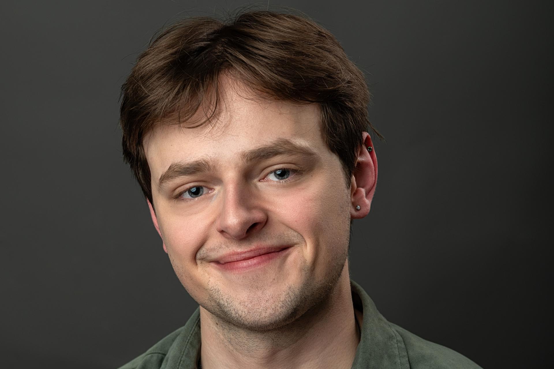headshot of smiling young man in green shirt