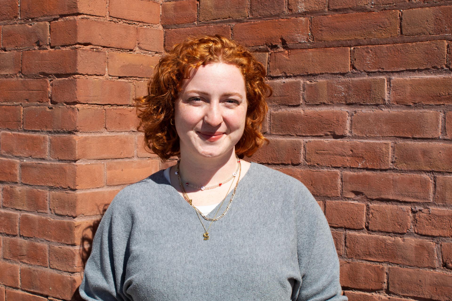 Student Sabina Ward standing in front of brick wall smiling