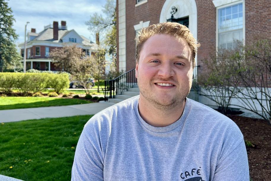 Austin Burnett sitting in front of Waterman Building at UVM