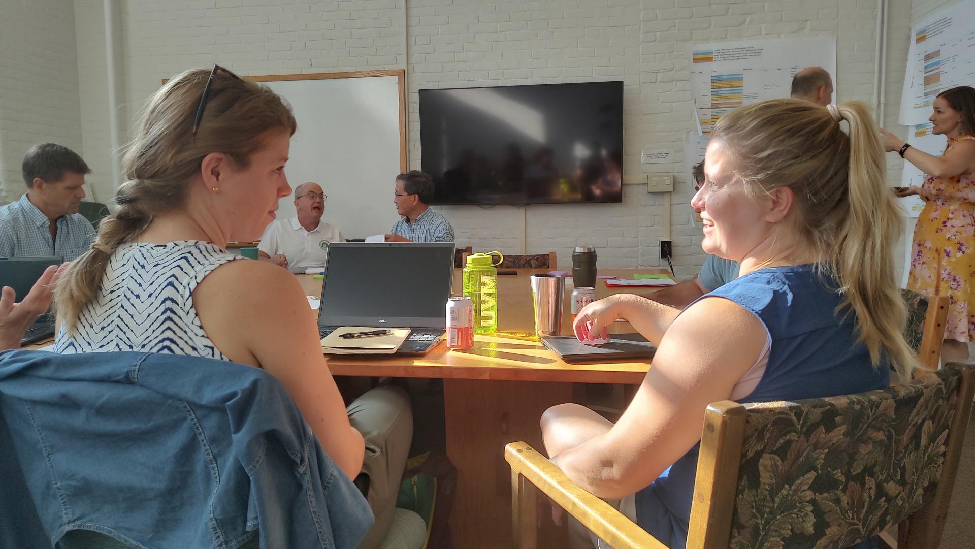 Two scientists talk at a table of peers