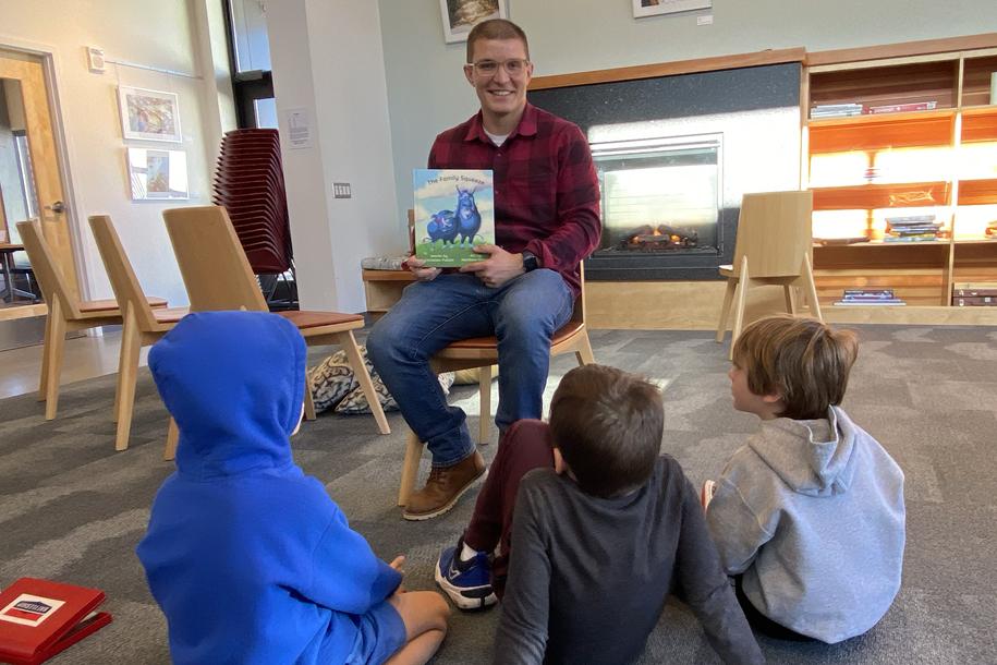 a man reading a book to a group of children