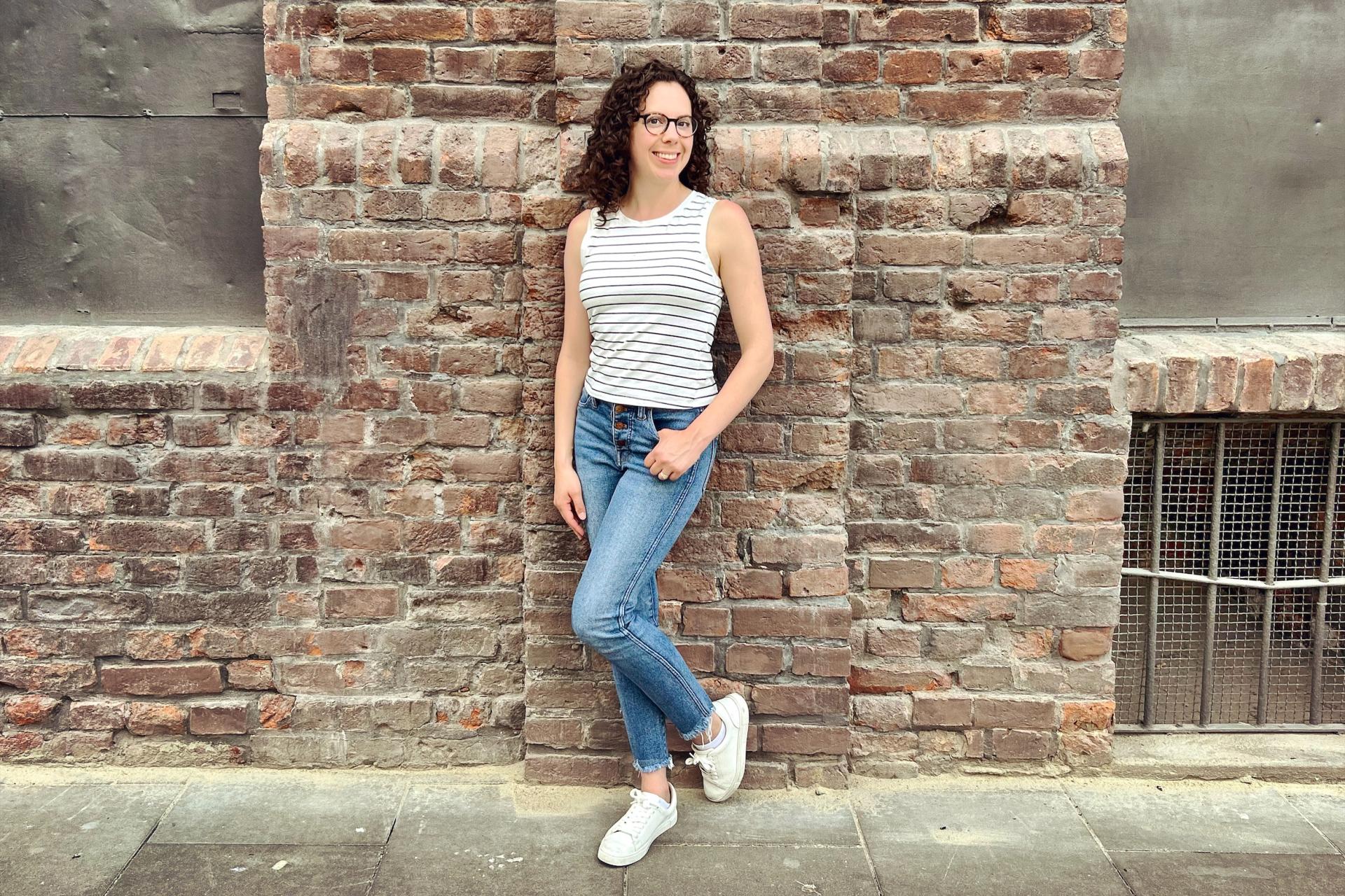 woman in jeans and sleeveless top standing in front of brick building