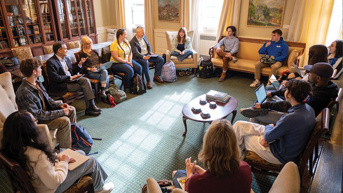a group of people sits in chairs in a circle having a conversation