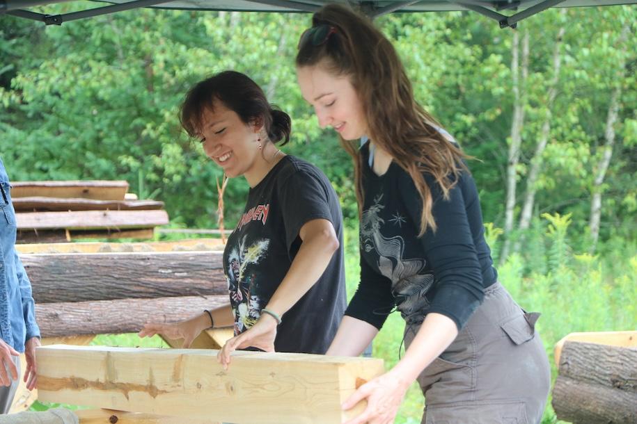 Two students holding large piece of lumber