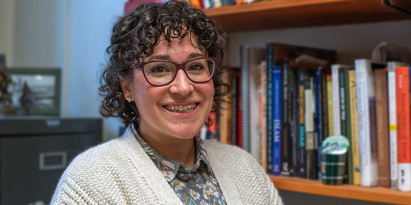 Ilyse Morgenstein Fuerst looking off camera surrounded by bureaus full of books