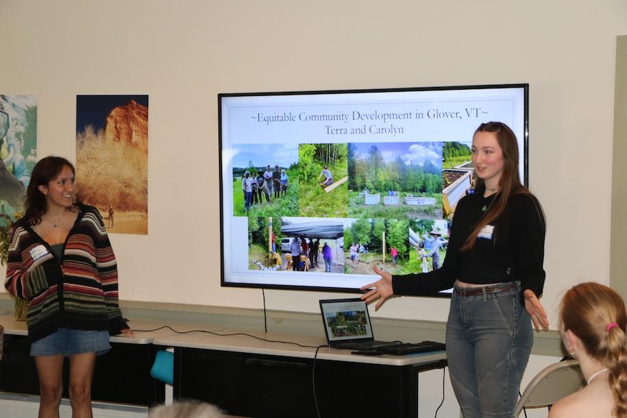 Two students stand in front of a large video screen