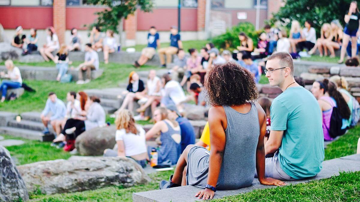 Many students sit together in an outdoor amphitheater