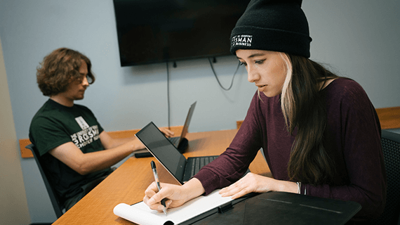 Lily sits at a table writing on a note pad