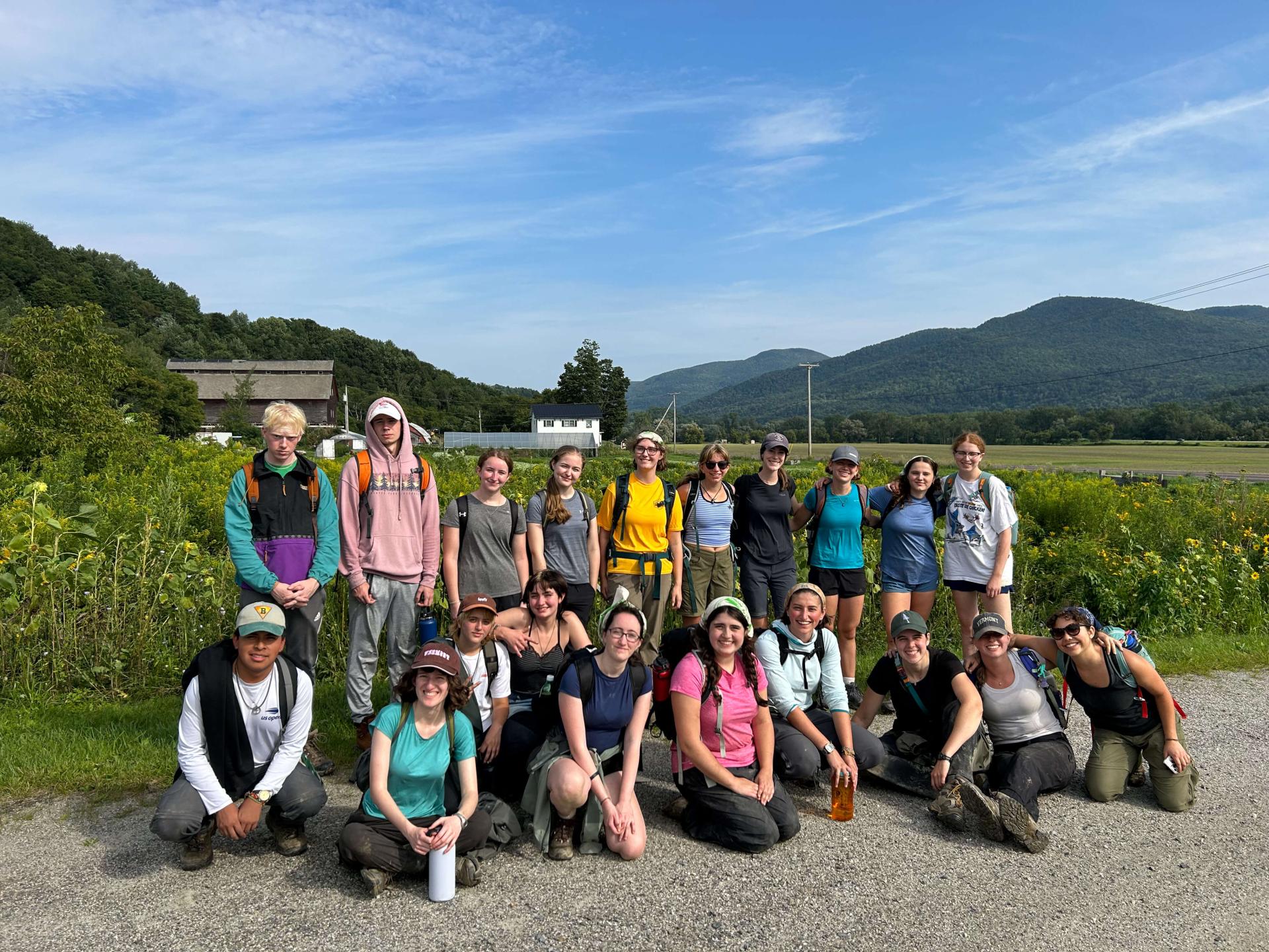 A group of SERVICE TREK students pose for a photo in a field during a beautiful sunny day 
