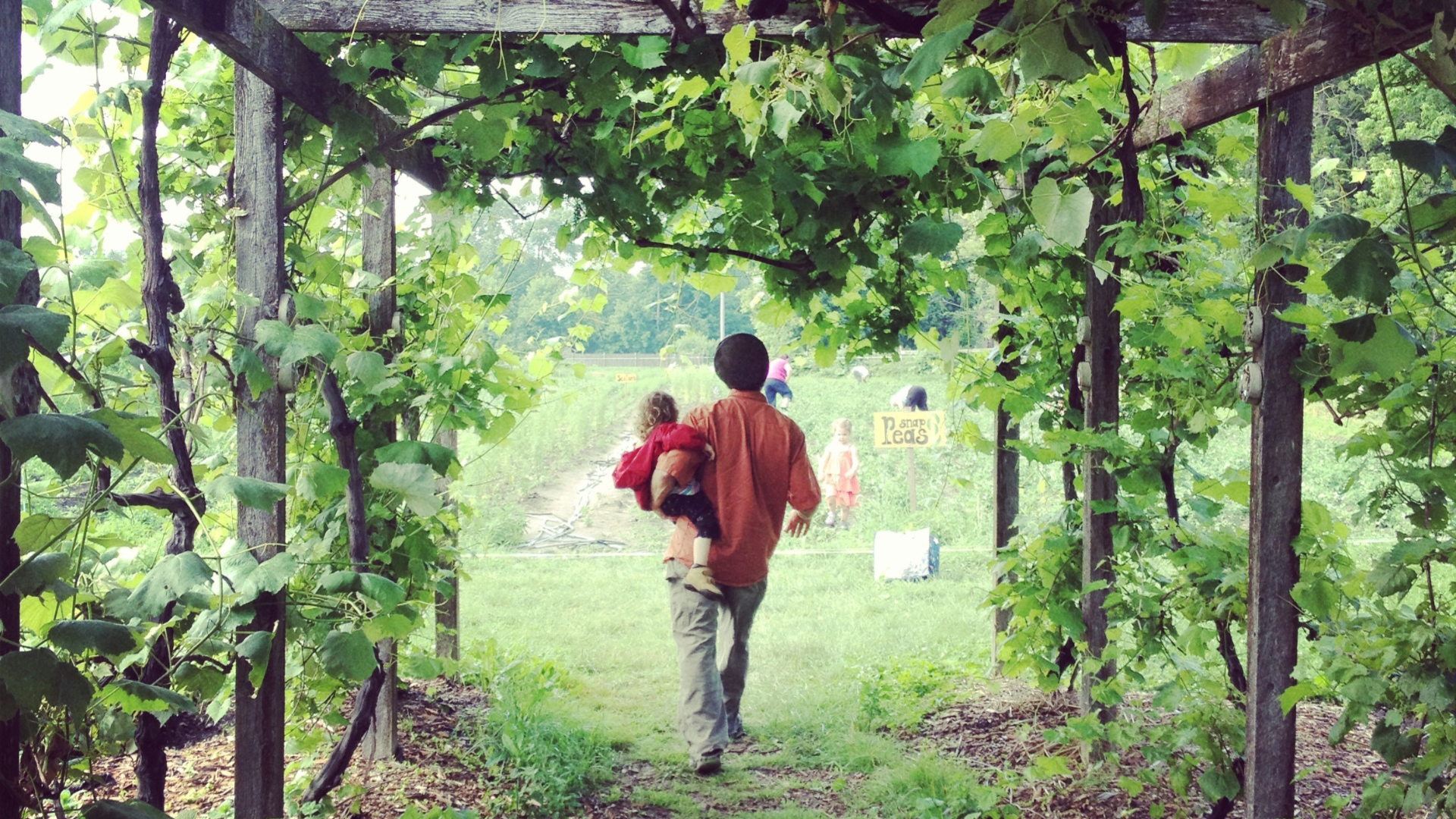 Person carrying a child, walking into a garden
