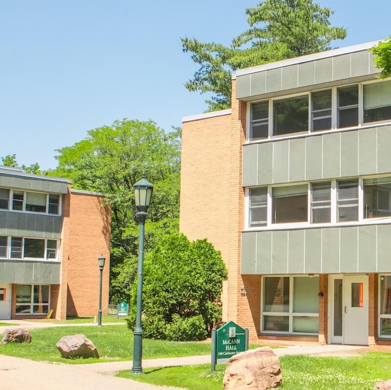 Two three-floor brick residence halls next to each other with grassy area between.