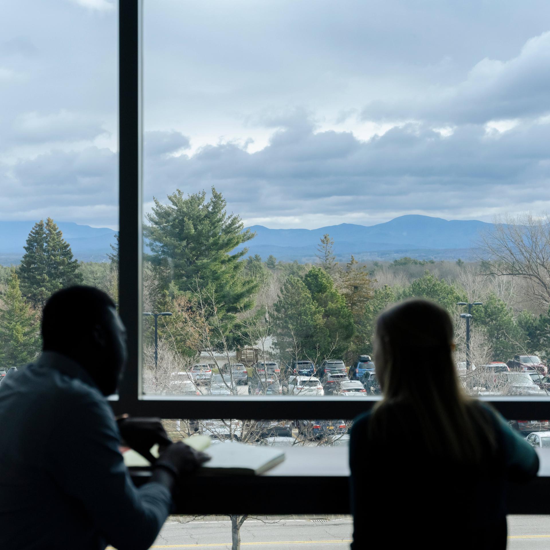 two people talking with mountains and clouds in the background