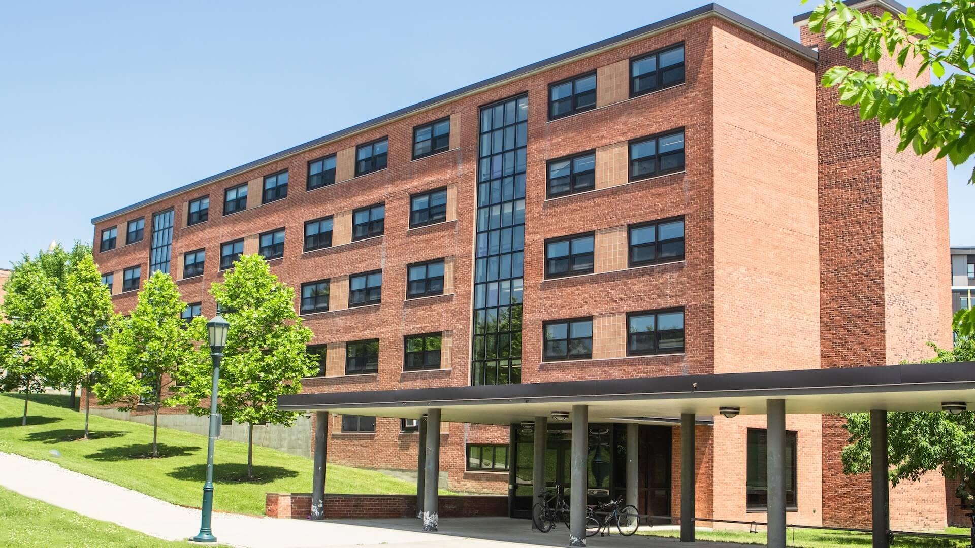 A five-story brick residence hall with trees and grassy area.