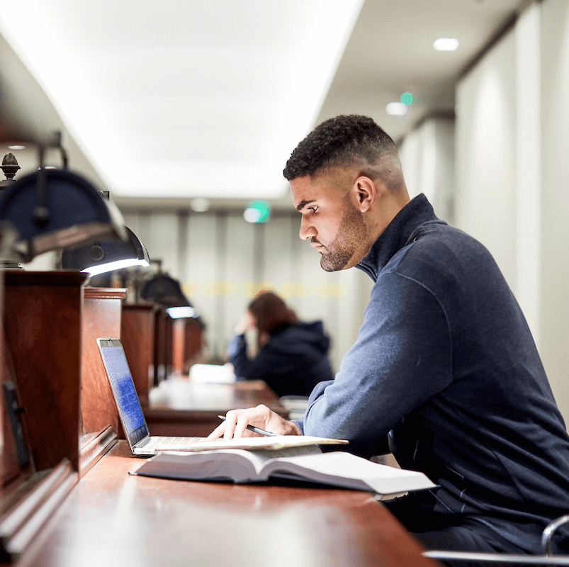 A student studies with a laptop and open book
