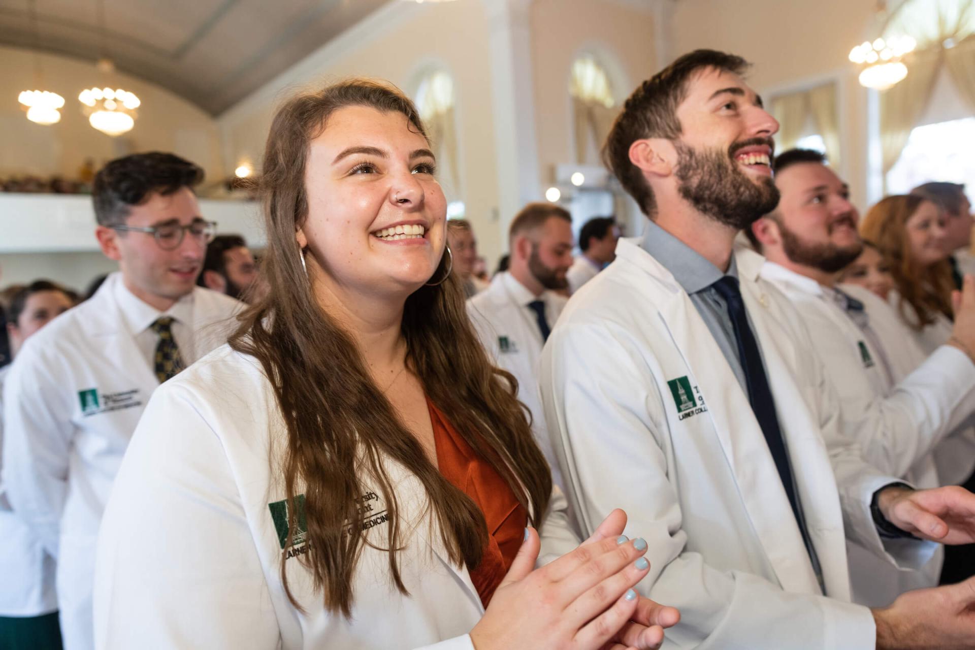 Students smiling in the audience at a LCOM White Coat Ceremony