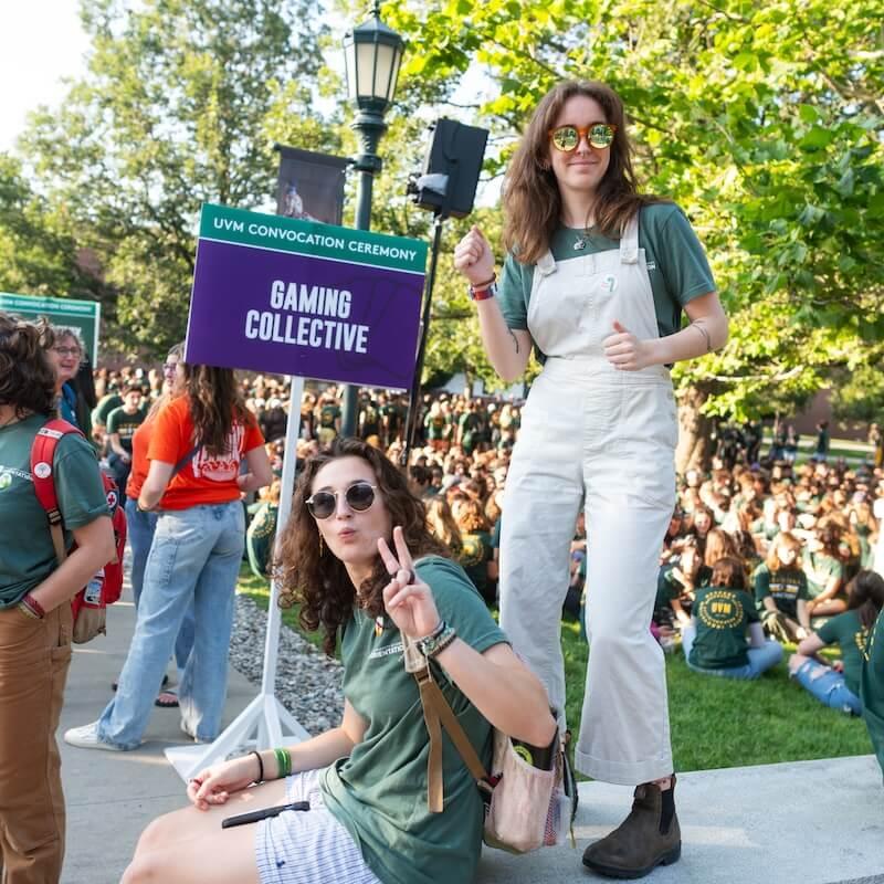 Two students standing near a purple sign that reads "Gaming Collective"