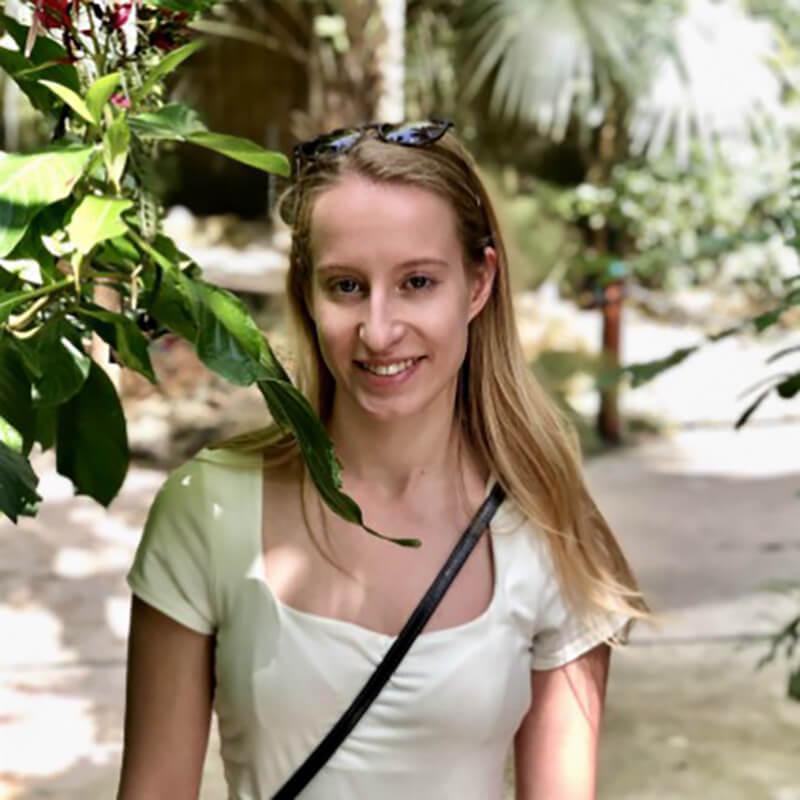 A student in a white shirt standing next to plants