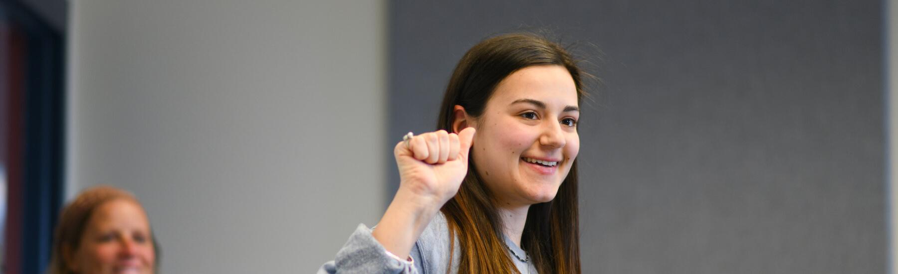 ASL student smiling as she works on signing in class.