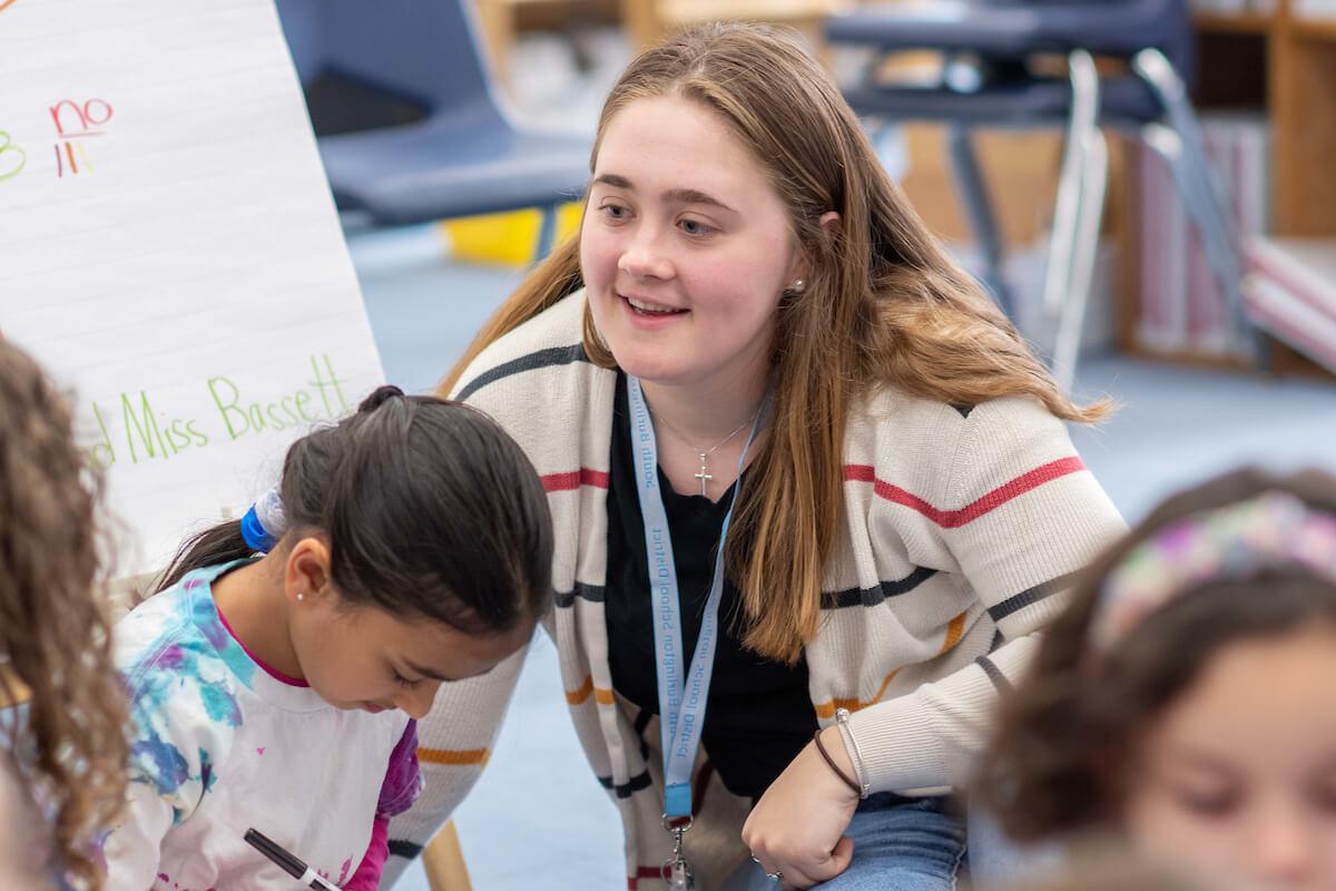 A student-teacher works with young children in the classroom