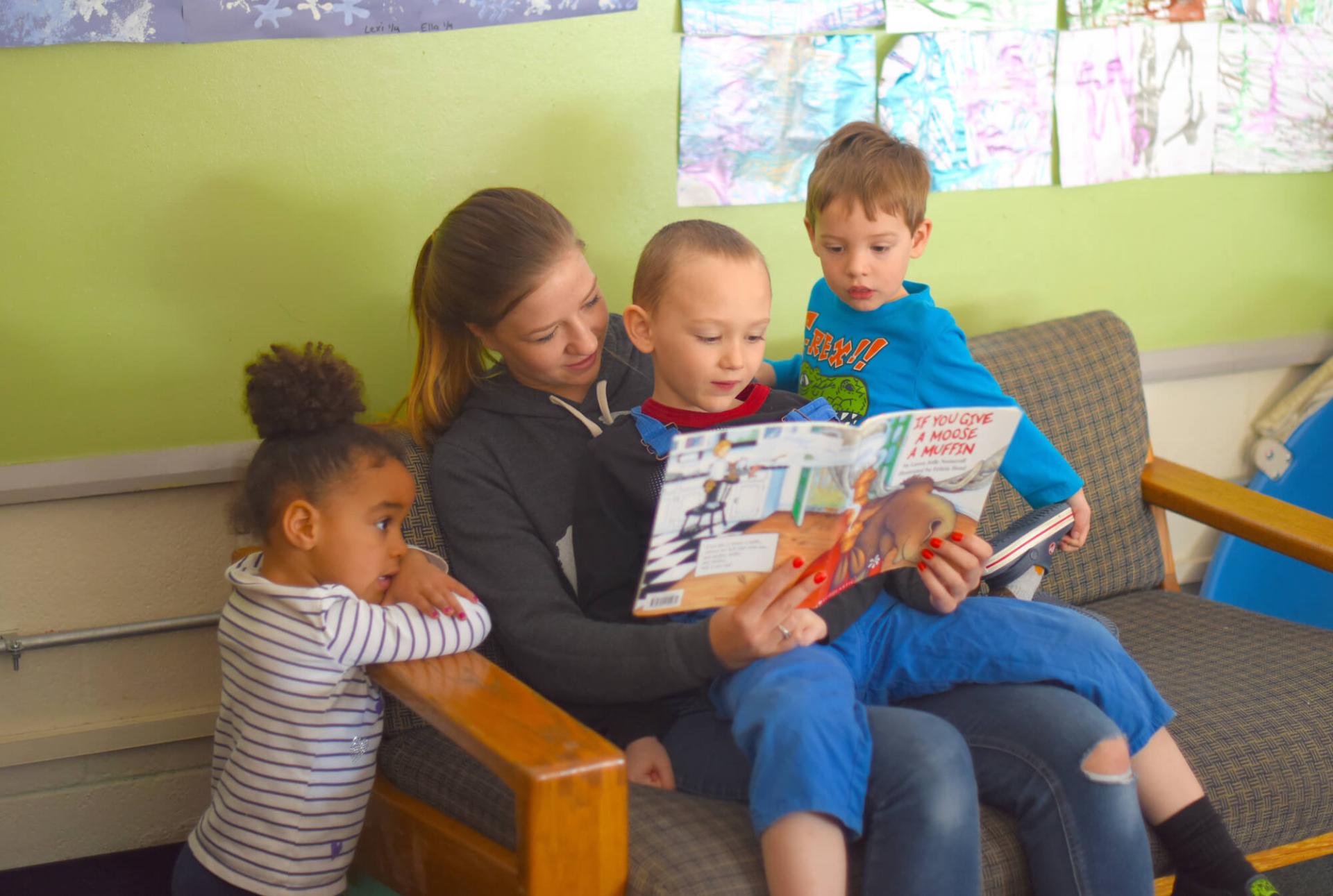 Early childhood special education intern reads with three children in a classroom.