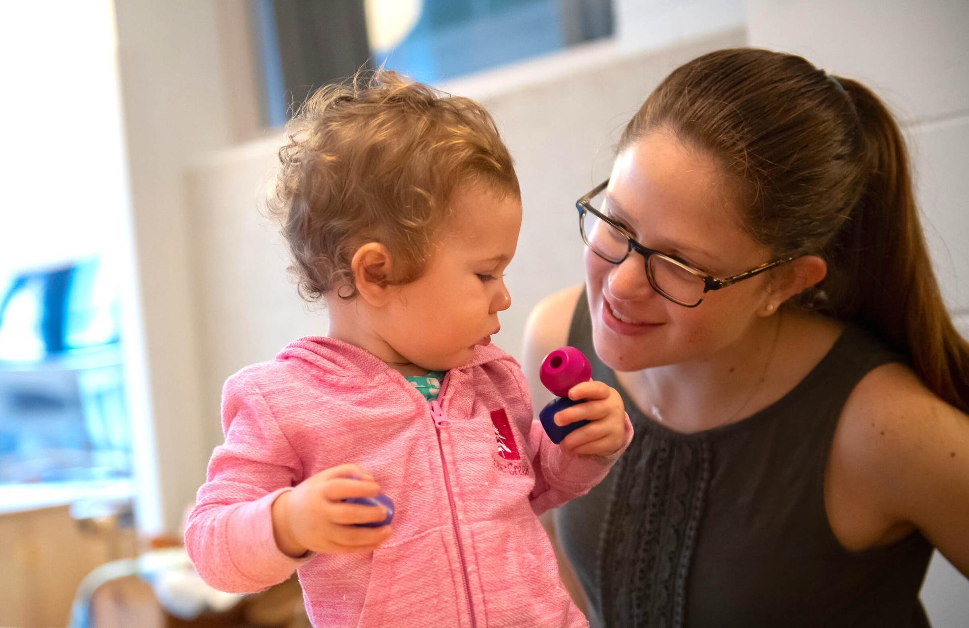 Student teacher works with a toddler in preschool classroom.