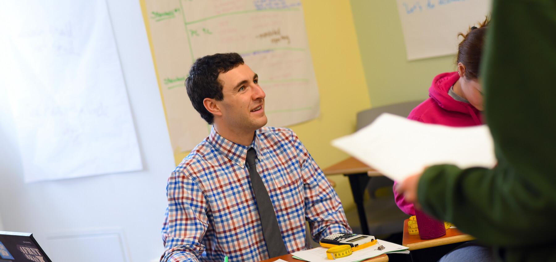 Educator engages with colleagues in a classroom meeting.