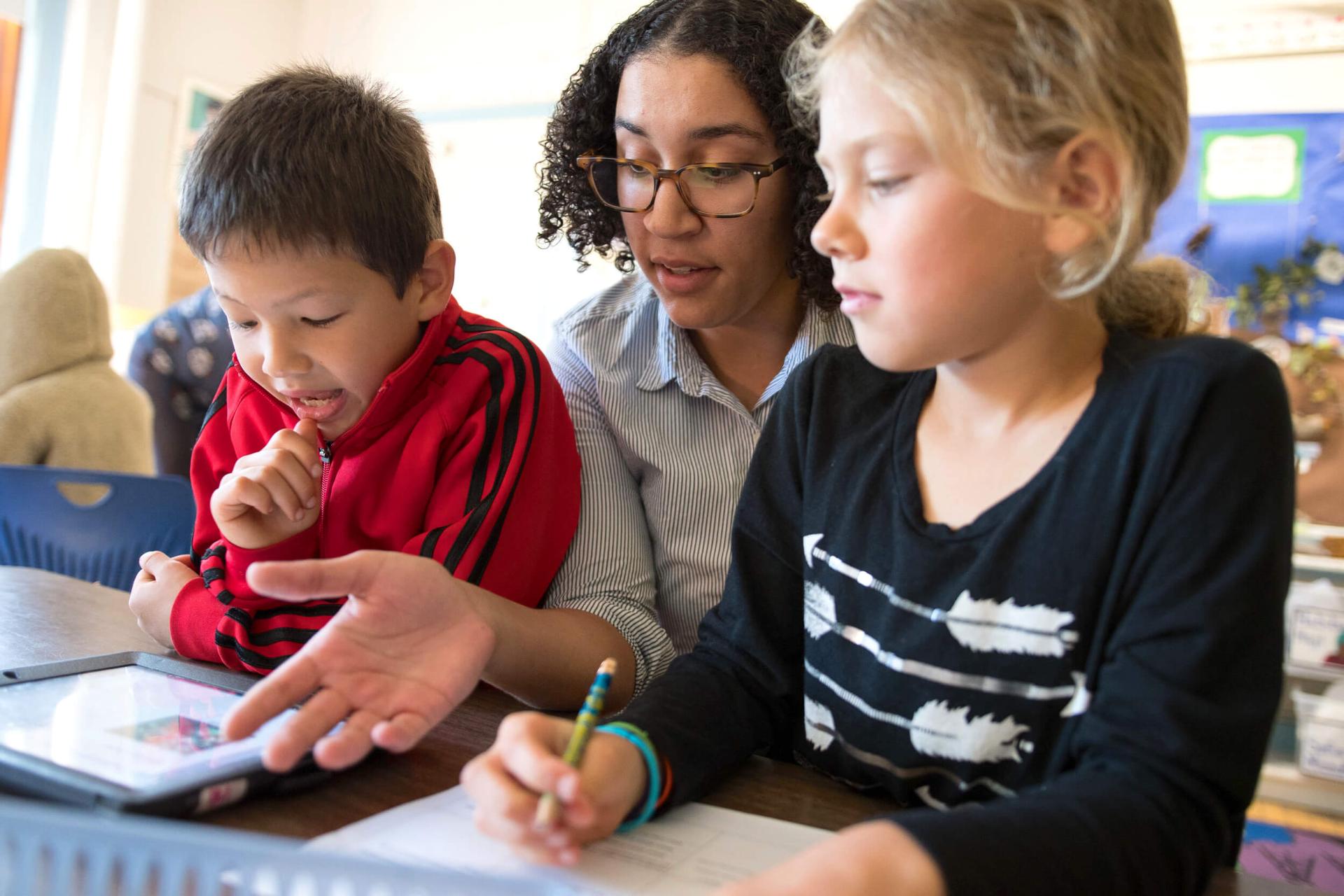 Student teacher works with two students in elementary school classroom during her student teaching internship.