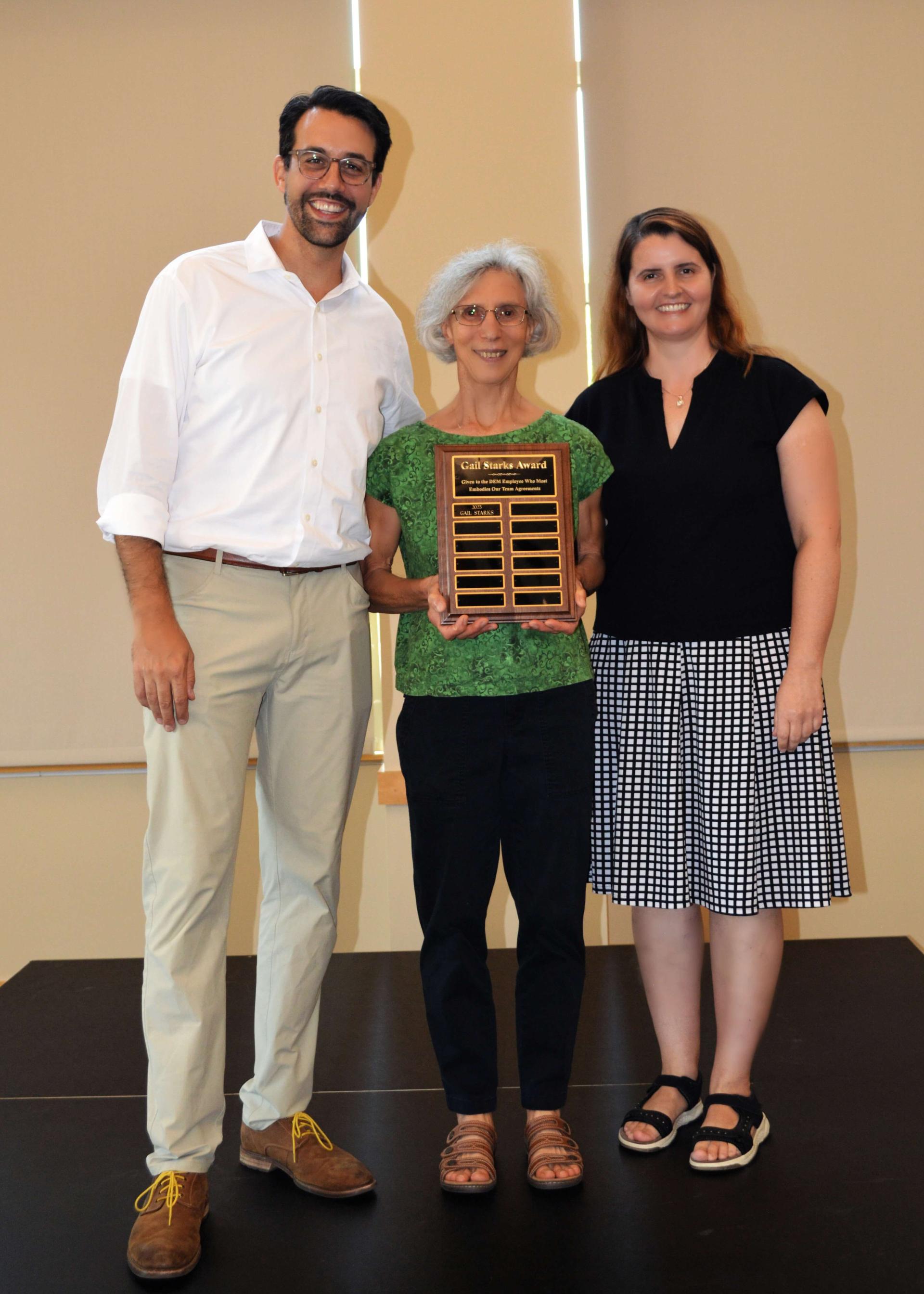 Gail Starks holding the award and posing for a photo with two other unnamed people