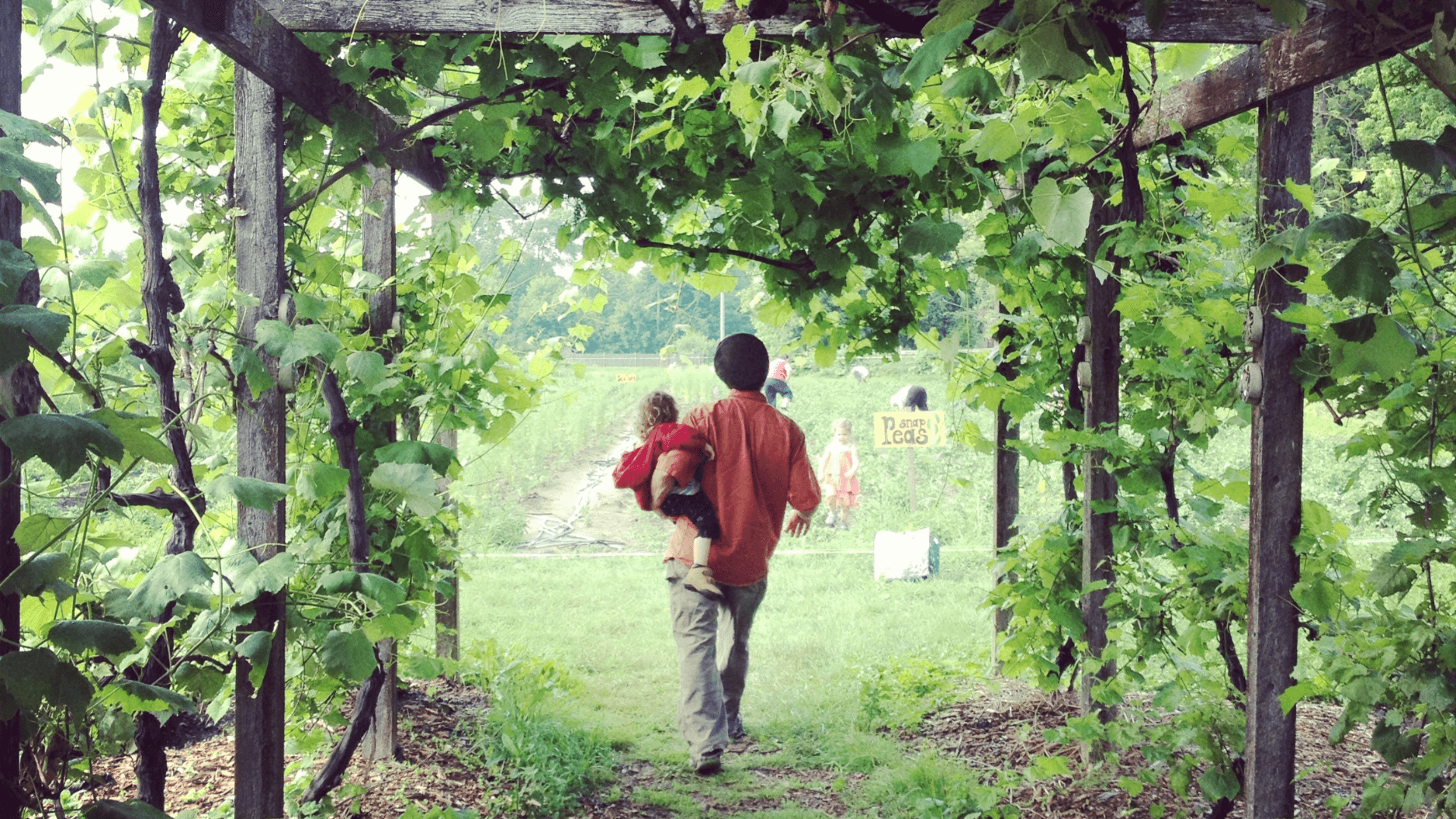 Person carrying a child, walking into a garden