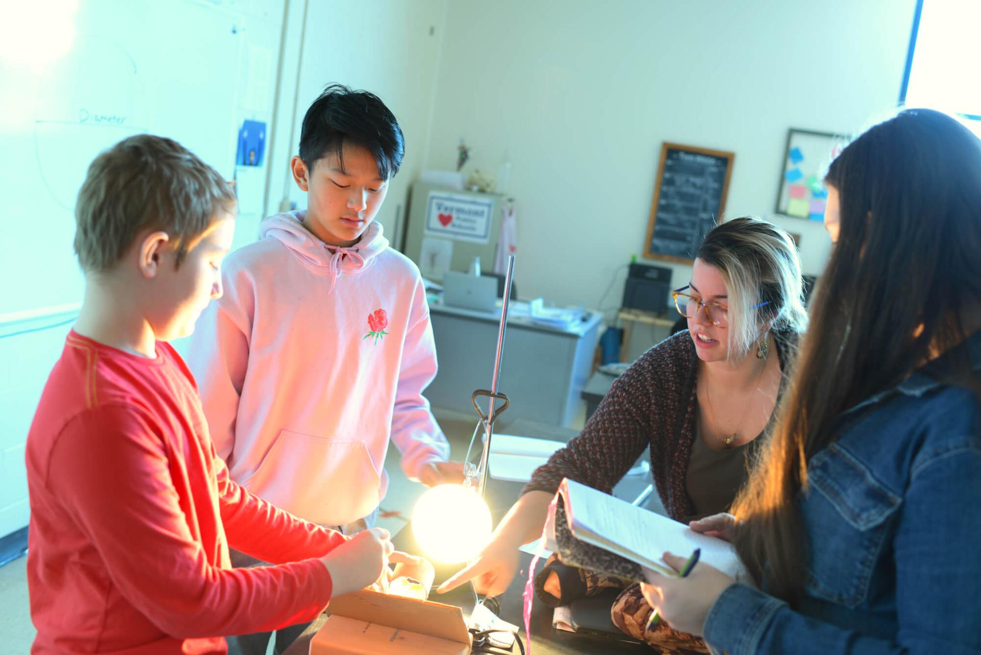 Student teaching intern works with students on a hands-on science project.