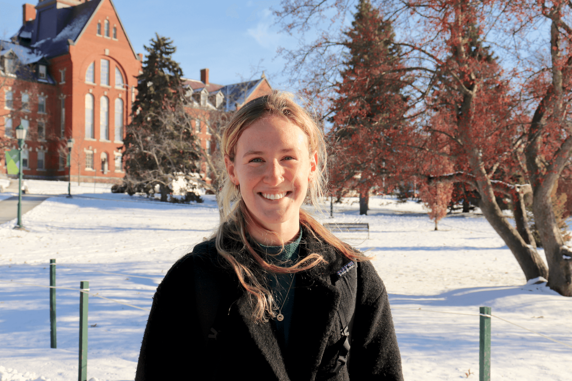 Phoebe Munch smiles as she stands on the University Green sidewalk on a sunny winter day