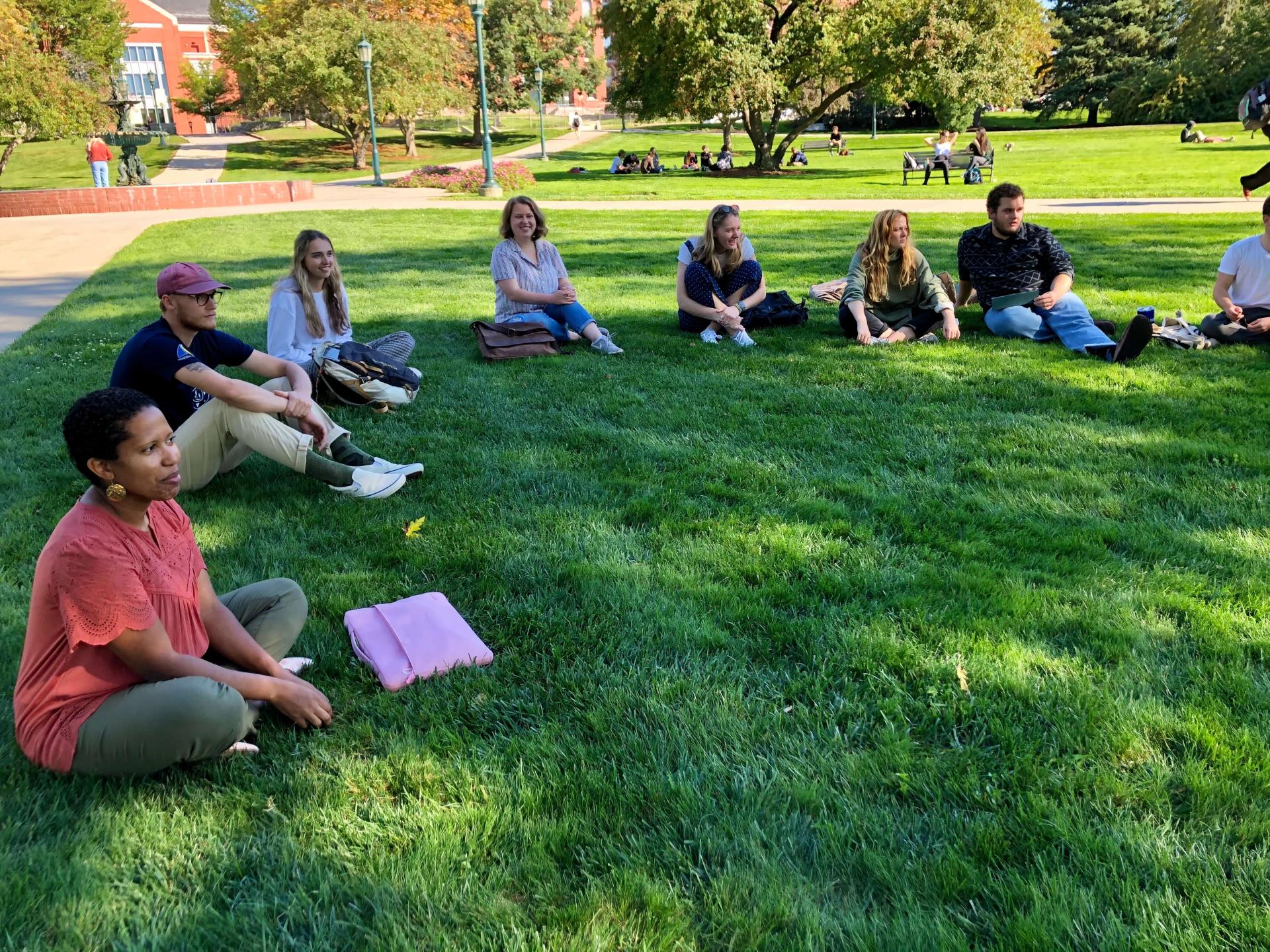 Professor Eliana Castro leads an fun activity with smiling students outside on the University Green.