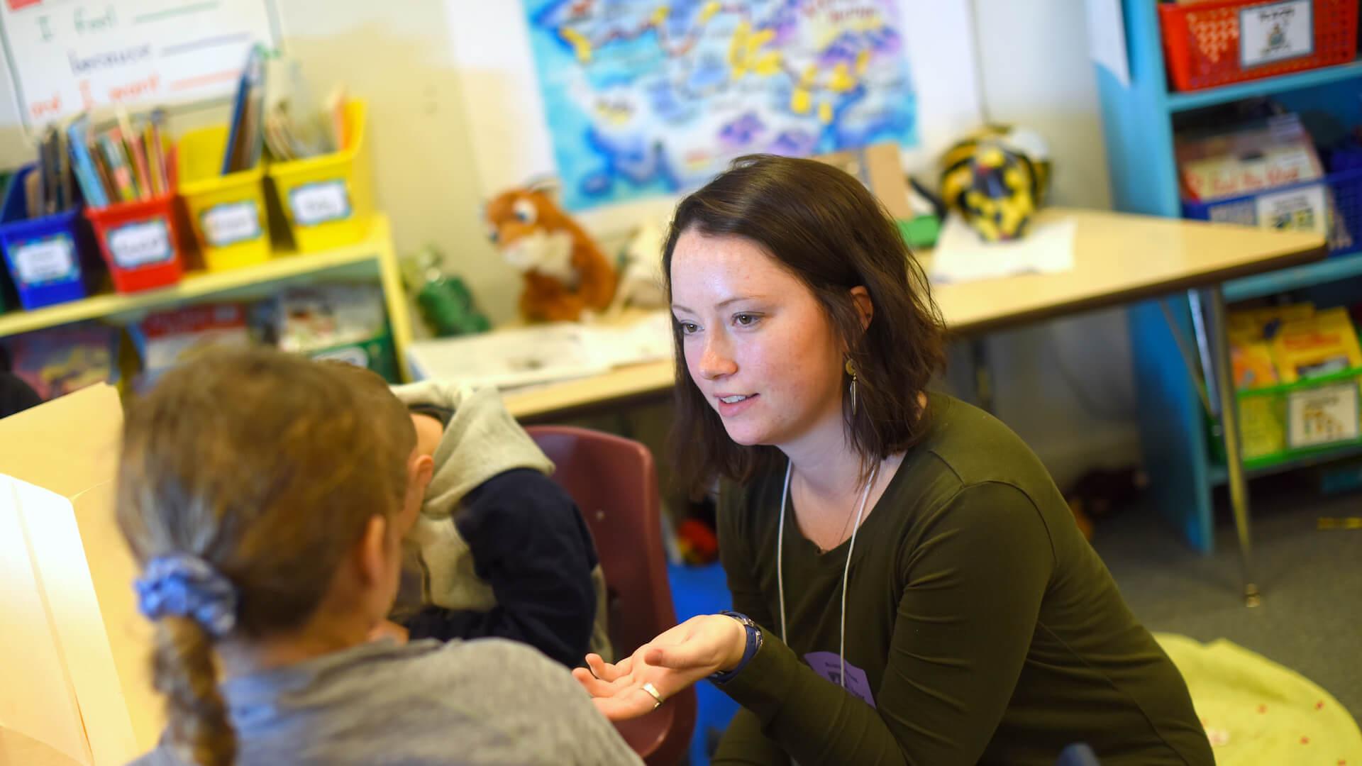 Student intern working one-on-one with a child in a school classroom.