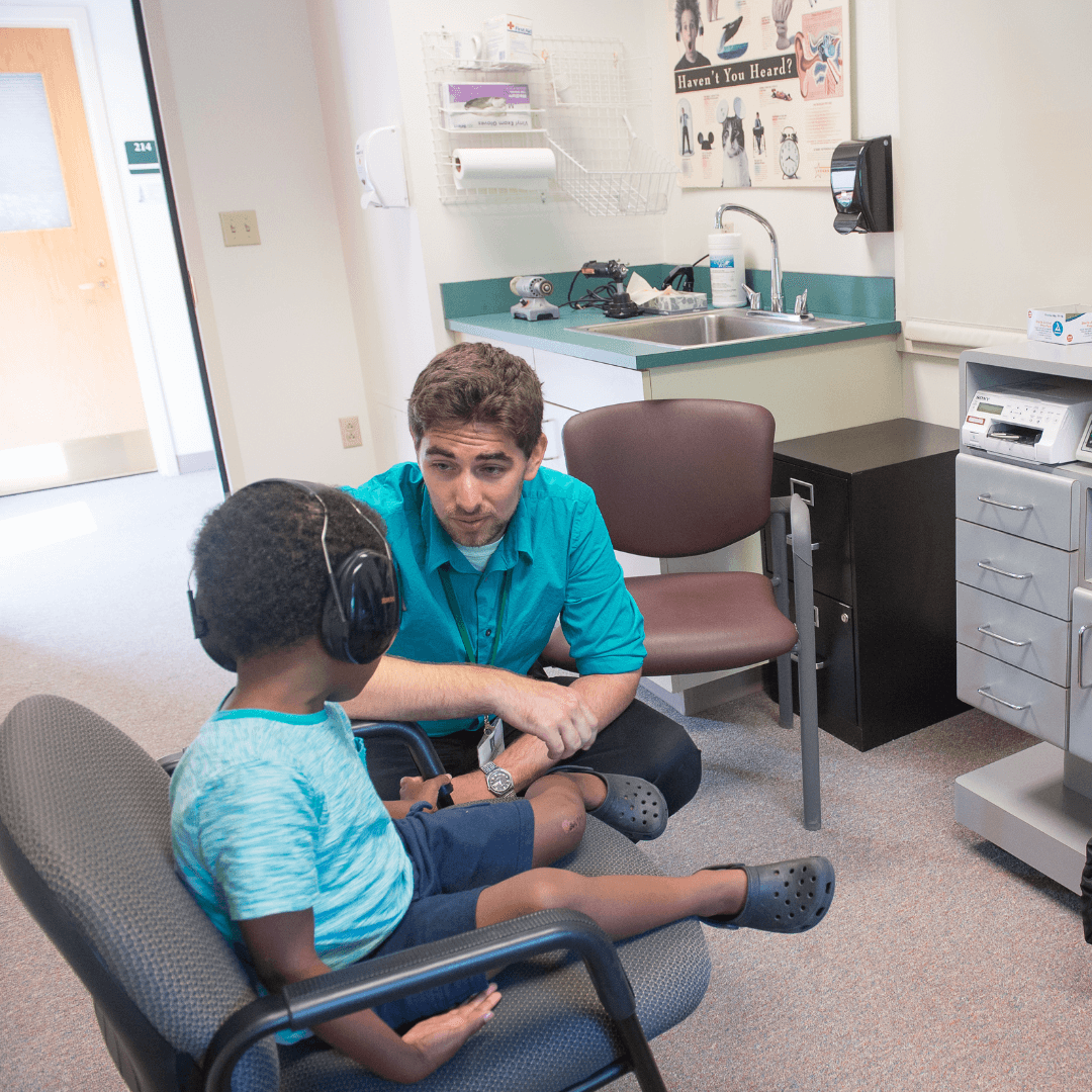 Man helping a child through a hearing test
