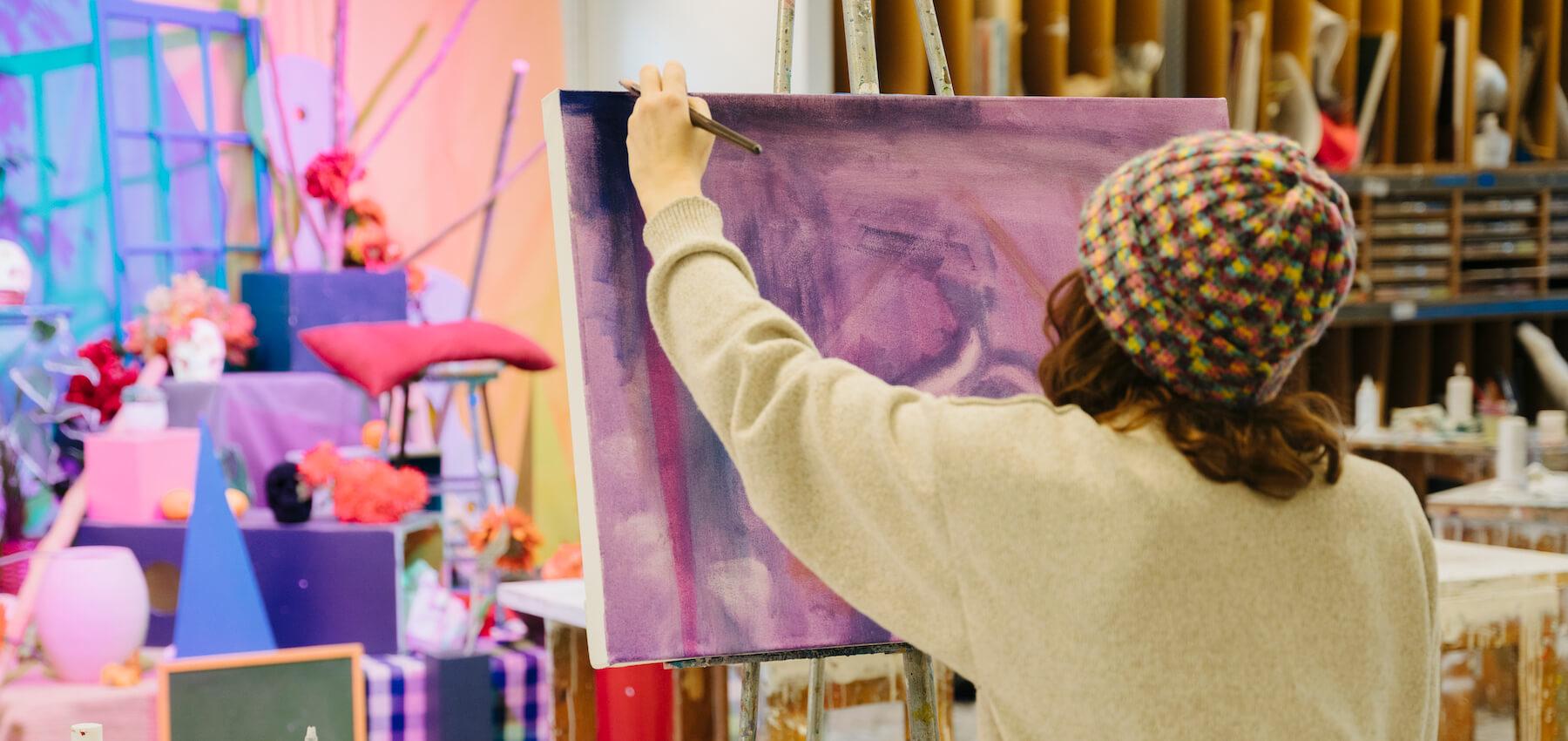 Student works on a colorful painting in a studio