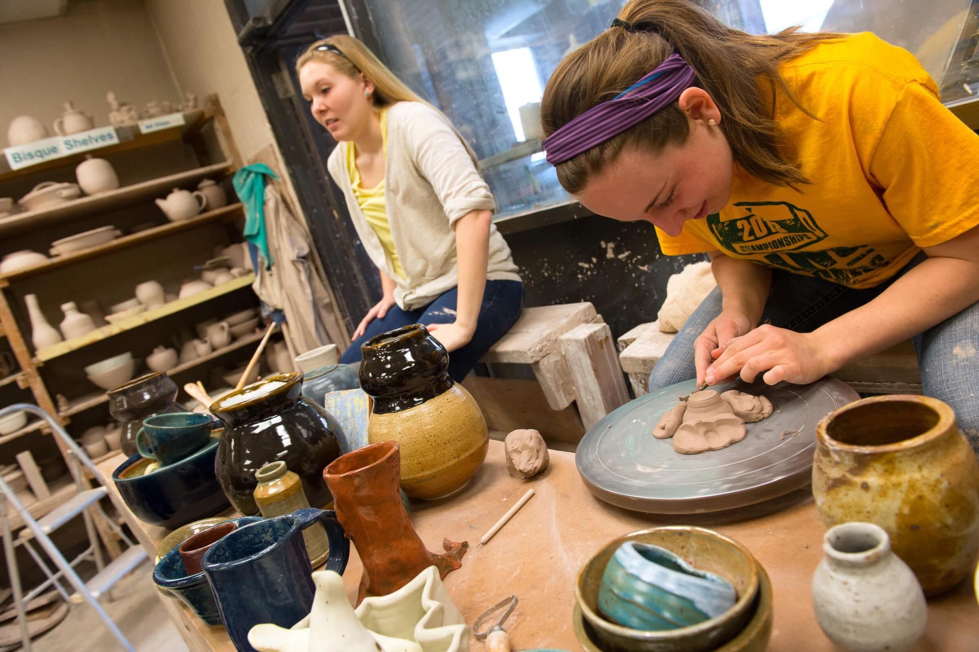 Students working to create pottery in a studio.