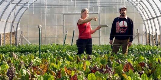 women pointing in a greenhouse