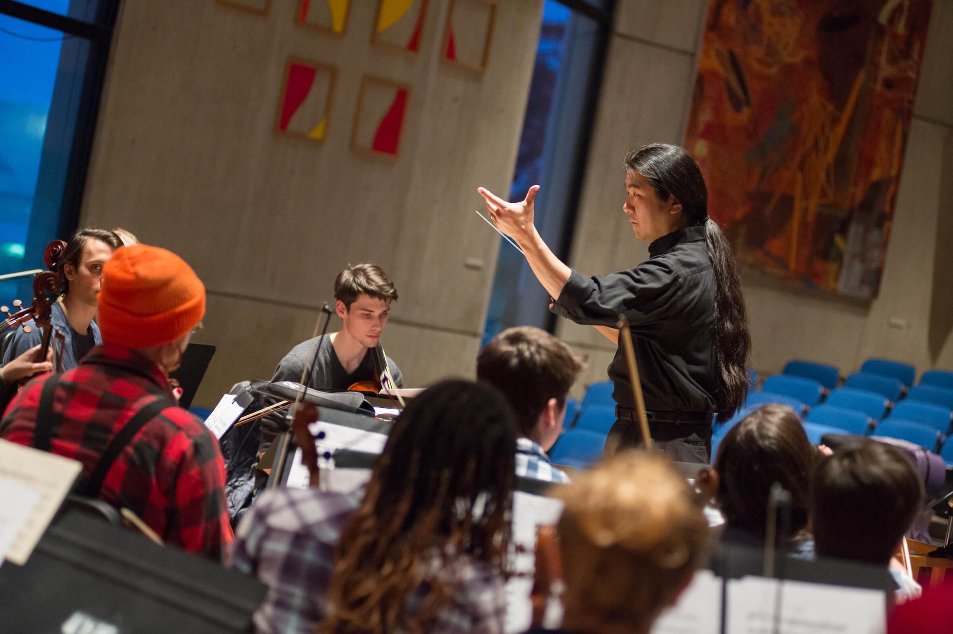 Students band practicing under the direction of a conductor.