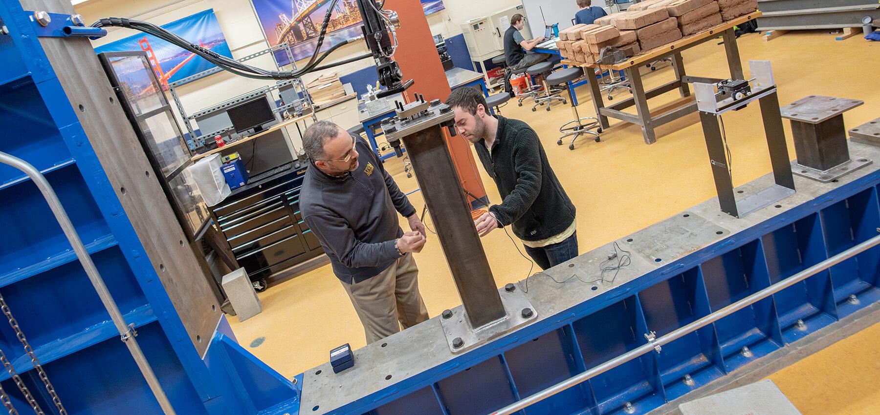 Professor demonstrating equipment to a student in the materials lab 