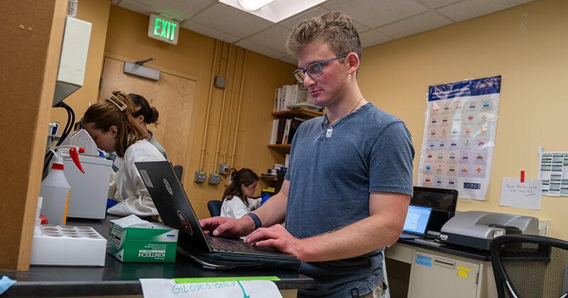 CEE undergraduate student conducting research on his laptop