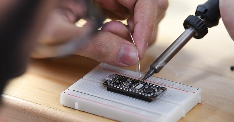 student soldering on a circuit board