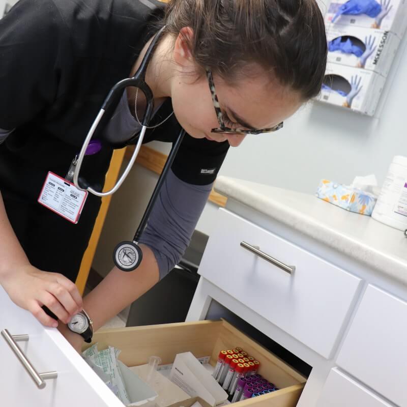 A nursing student inventories supplies in the clinic