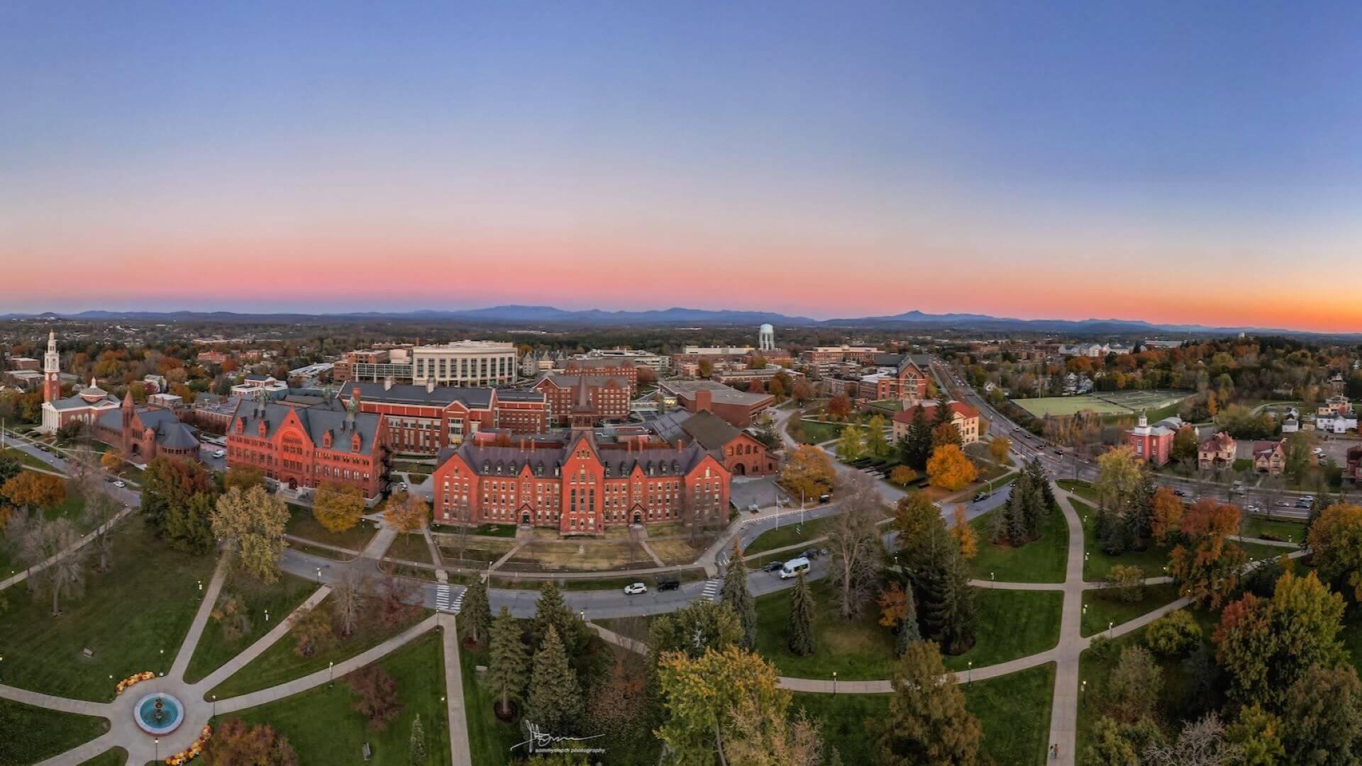 Drone shot of campus at sunrise with purple skies and mountains behind University Row