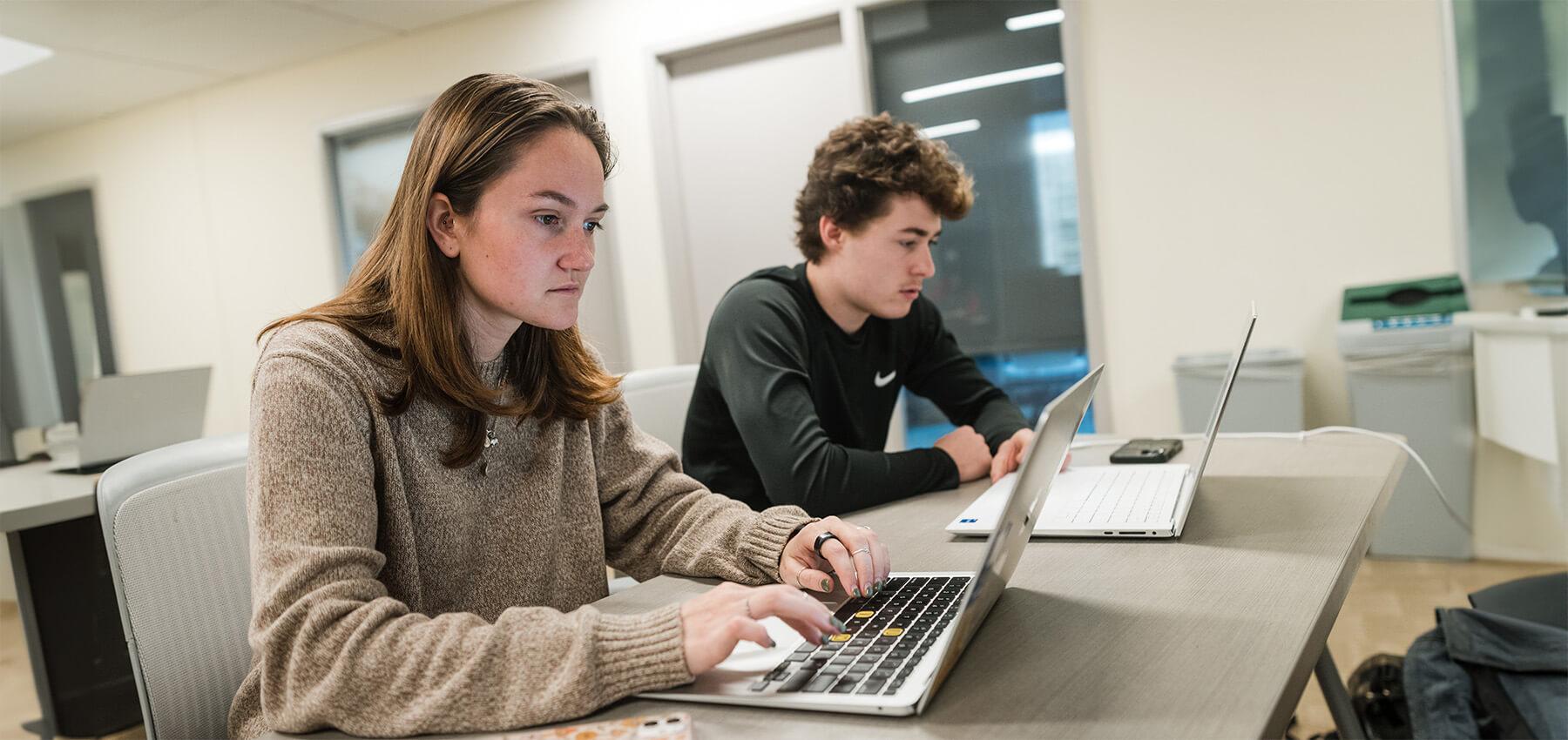 Two CEMS students at work on their laptops